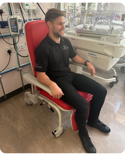 Man sat in Kangaroo Recliner next to incubator.
