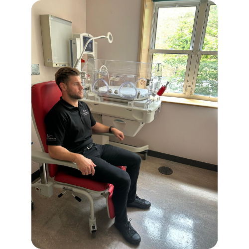 Man sat in kangaroo Recliner next to incubator. Man sat in kangaroo Recliner next to incubator.
