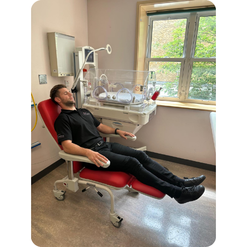 Man laying in Kangaroo Recliner chair next to incubator in semi-reclined position. Man laying in Kangaroo Recliner chair next to incubator in semi-reclined position.