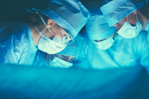 Medical staff wearing scrubs and performing surgery in an operating theatre. Medical staff wearing scrubs and performing surgery in an operating theatre.