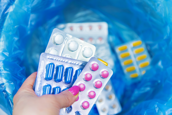 Packaged tablets being put in medicine wastebin. Packaged tablets being put in medicine wastebin.