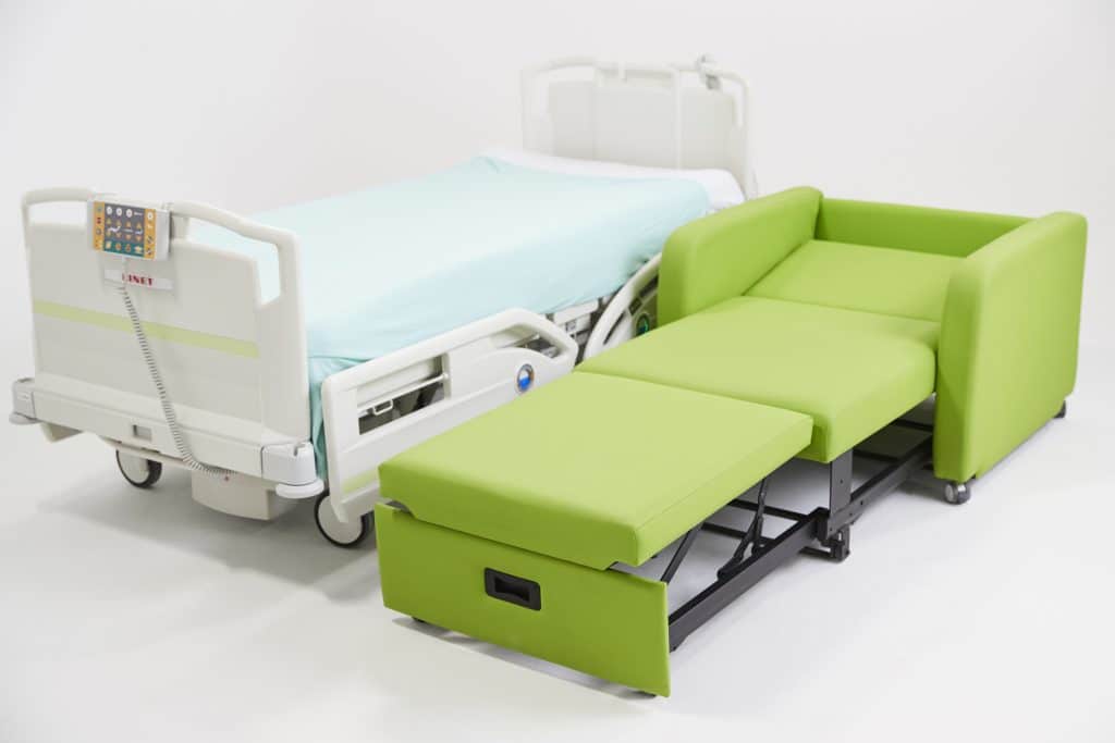 Green overnight sleeper chair next to patient bed