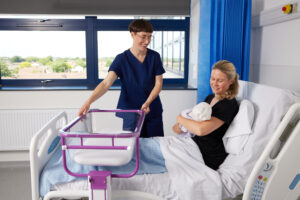 The Croyde Height Adjustable Overbed Cot glides under the bed, putting baby in front of Mum